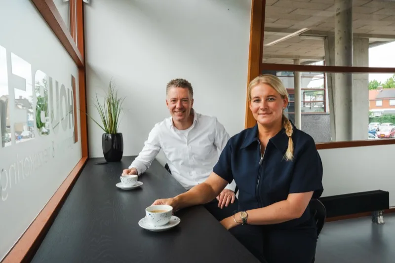 Twee collega's in gesprek aan tafel, met koffie