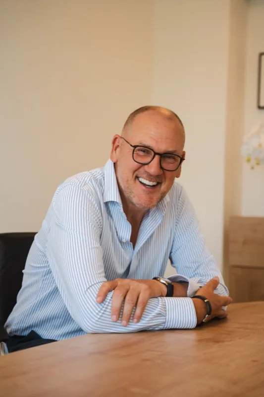 Lachende ondernemer met bril aan een houten tafel