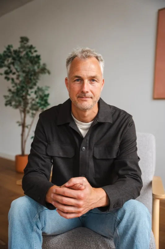 Portret van een ondernemer in een fauteuil, met een plant op de achtergrond
